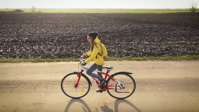 Aerial drone view girl rides bicycle on countryside road in yellow jacket