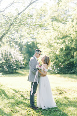 Naklejka premium Wedding couple in the Park hugging and kissing. Photo shoot in the style of fine art in nature.
