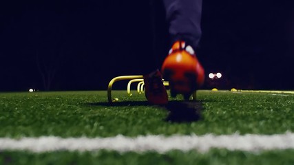 Soccer agility training equipment. Professional football player with training hurdles at night. 4k slow motion