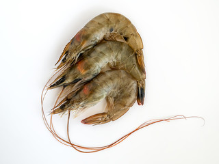 Three uncooked king prawns on white background. Delicacy, tasty and healthy sea food, close up, top view