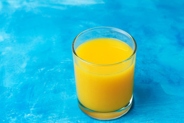 Glass of the fresh orange juice on a blue background