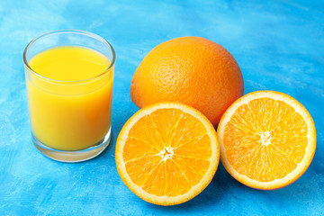 Orange fresh drink, glass of juice and ripe citrus fruits on a blue background