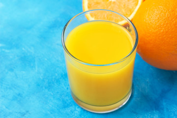 Orange fresh drink, glass of juice and ripe citrus fruits on a blue background