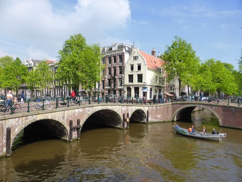 Canal et pont à Amsterdam, avec un petit bateau de touristes (Pays-Bas)