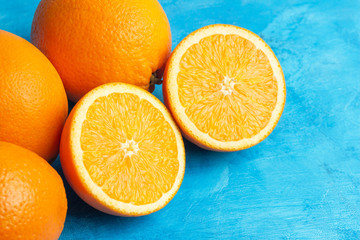 Halves and whole ripe orange citrus fruits on a blue background