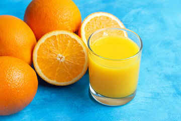 Orange fresh drink, glass of juice and ripe citrus fruits on a blue background