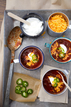 mugs of chili on metal tray with toppings