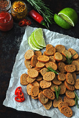 Rye crackers with spices on paper. Croutons with rosemary, lime and chilli. Vegan snack