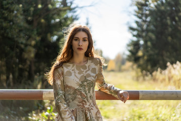 Young woman with long red hair in a linen dress gathering mushrooms in the forest in the bast basket