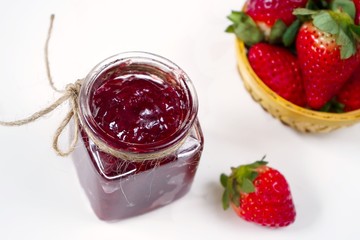 Strawberry jam in a jar on white background with fresh berries on side