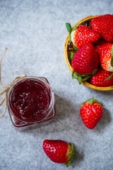 Strawberry jam or preserve in a jar and strawberrieson the side basket