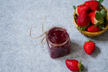 Strawberry jam or preserve in a jar and strawberrieson the side basket