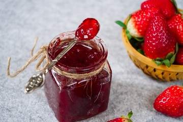 Strawberry jam or preserve in a jar and strawberrieson the side basket