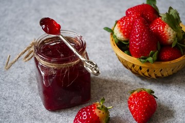 Strawberry jam or preserve in a jar and strawberrieson the side basket