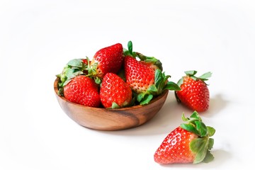 Fresh strawberries in a wooden bowl isolated on white
