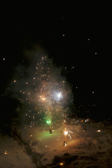 Bright colorful multicolored fireworks fountain in the snow at night