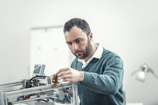 Serious smart adult technician fixing 3d printer
