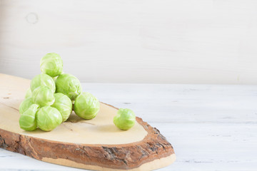 a pile of Brussels sprouts on a white wooden background, close up, space for text