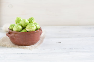a pile of Brussels sprouts in a clay bowl on a white background, space for text