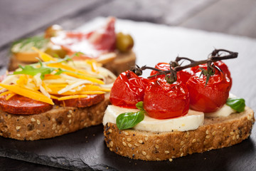 Set of different bruschettas on dark wooden table. Front view and copy space.