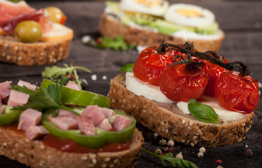 Set of different bruschettas on dark wooden table.