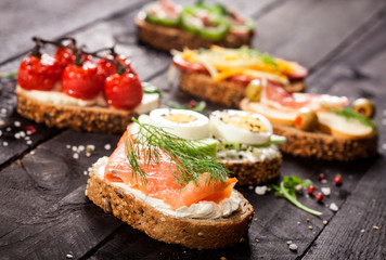 Set of different bruschettas on dark wooden table.