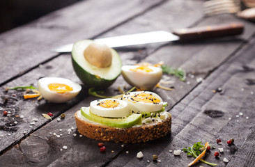 Bruschetta with avocado, cheese, egg, sesame on wooden table