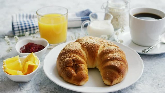 Served breakfast with baked golden croissant and jam with glass of orange juice on marble table
