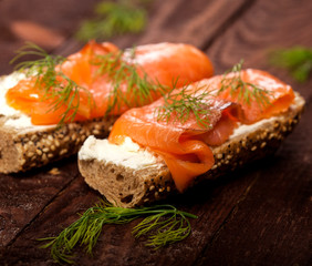 Bruschettas with cream cheese, salmon and dill on wooden table