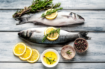Fresh fish sea bass. Sea bass raw fish with ingredients spices and herbs on wooden background