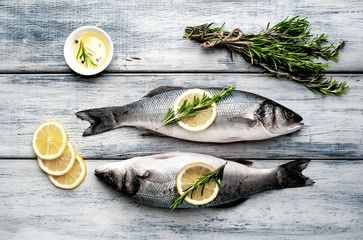 Fresh fish sea bass. Sea bass raw fish with ingredients spices and herbs on wooden background