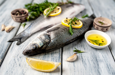 Fresh fish sea bass. Sea bass raw fish with ingredients spices and herbs on wooden background