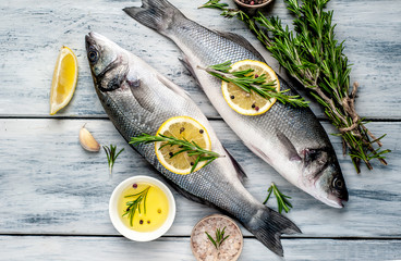 Fresh fish sea bass. Sea bass raw fish with ingredients spices and herbs on wooden background