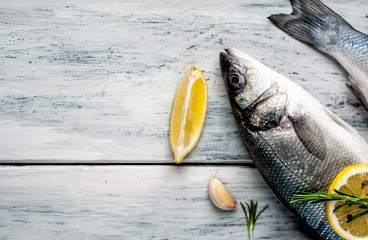 Fresh fish sea bass. Sea bass raw fish with ingredients spices and herbs on wooden background . Top...