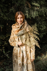 Young woman with long red hair in a linen dress gathering mushrooms in the forest in the bast basket