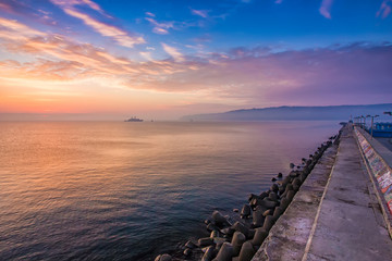 Black sea at a beautiful sunrise, breakwater and ship in the light of the rising sun, Varna, Bulgaria
