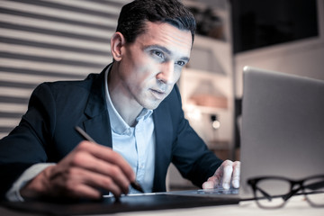 Professional smart man taking notes while working