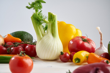 Composition still life of a bunch fresh different seasonal green vegetables avocado, fennel, garlic, onion, tomato, red yellow peper. Concept of healthy food and nutrition.