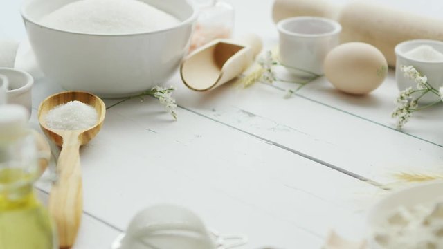 Assorted ingredients for pastry preparation and cooking tools lying in circle on white timber tabletop