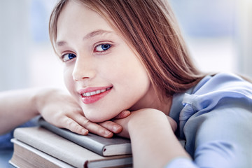 Positive happy girl smiling with hands on books