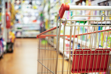 Shopping trolley cart against supermarket aisle blurred background