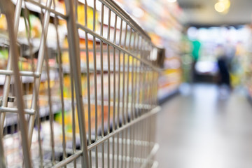 Shopping trolley cart with shallow DOF against supermarket aisle background