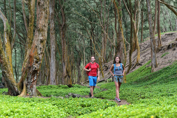 Hiking couple tourists walking together in forest trail path in summer travel vacation destination...