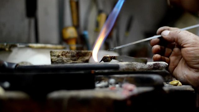 Master jeweler welding an ornament in a jewelry workshop. Image of hands and product close up.