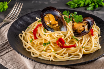 Homemade pasta spaghetti with mussels, peppers and parsley on rustic background. Sea food meal.