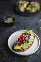 Avocado toast with seeds and sprouts on black table, close up.