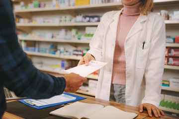 Customer handing over a prescription to the chemist - obrazy, fototapety, plakaty