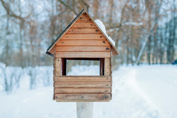 Obraz na płótnie Canvas Winter landscape. Wooden birdhouse in snow-covered garden. Blurry photography with a shallow depth of field. Cold winter day.