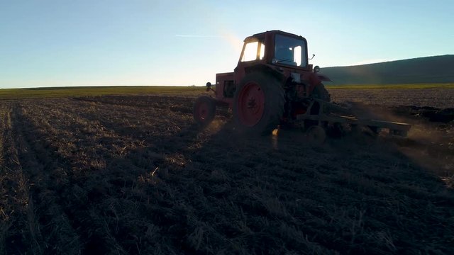 Harvest fields with tractor. Farmer plowing stubble field.