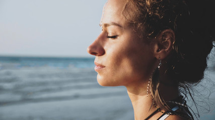 Profile portrait of young pretty woman standing on the beach